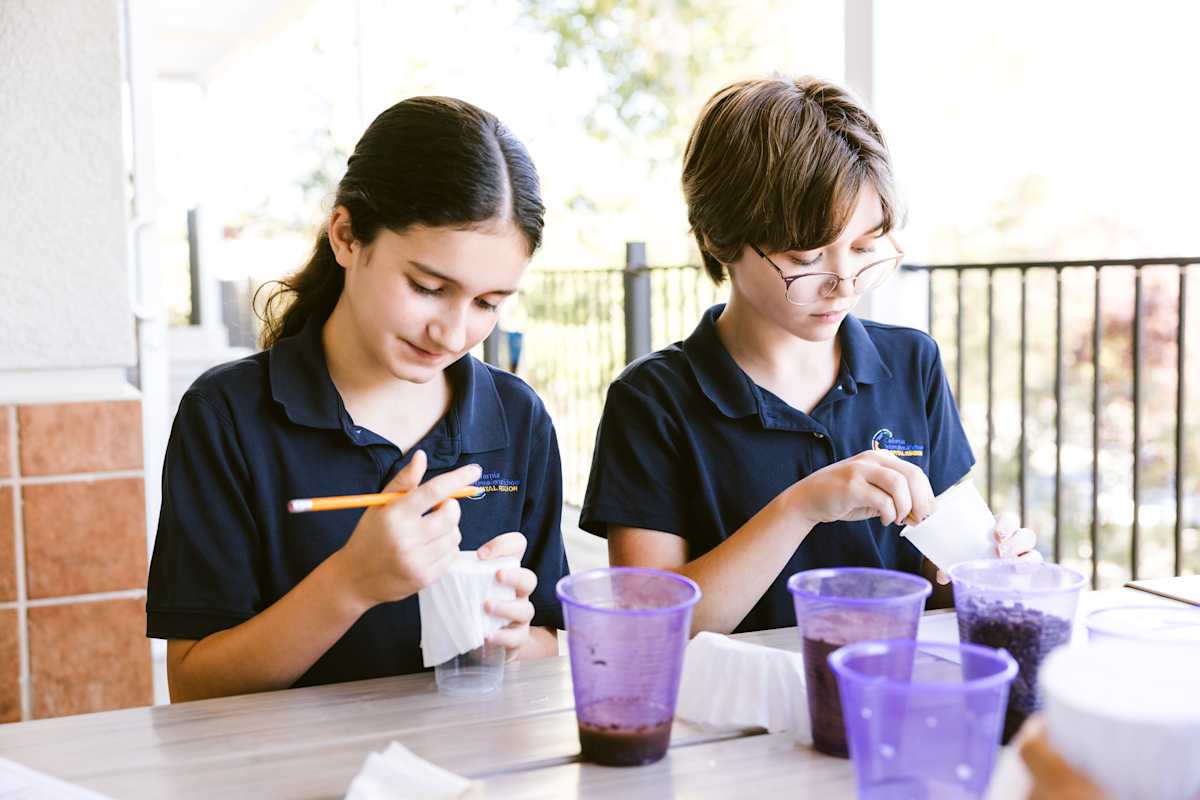 Two Young students engaged in hands-on STEAM learning activities at their classroom tables, working with educational materials and projects