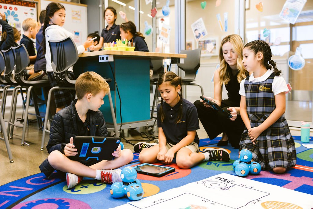 A teacher instructing kids on using robots in the Makerspace.