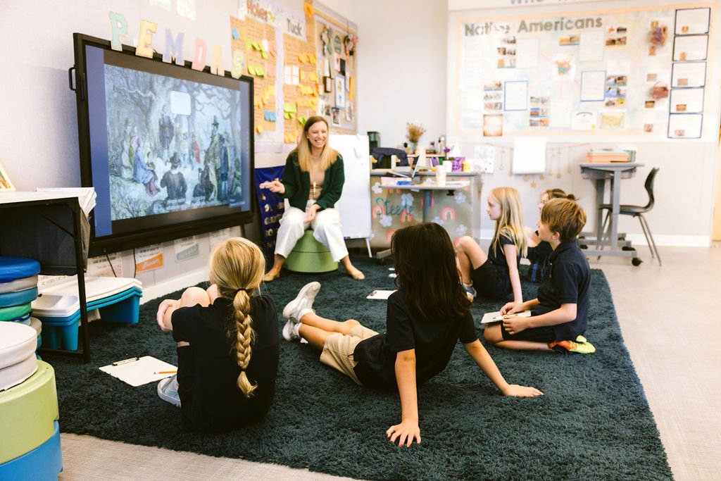 Teacher leading interactive group discussion with students seated on classroom floor