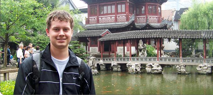 Matt Holt stands in front of a koi pond and building in Yiwu, China