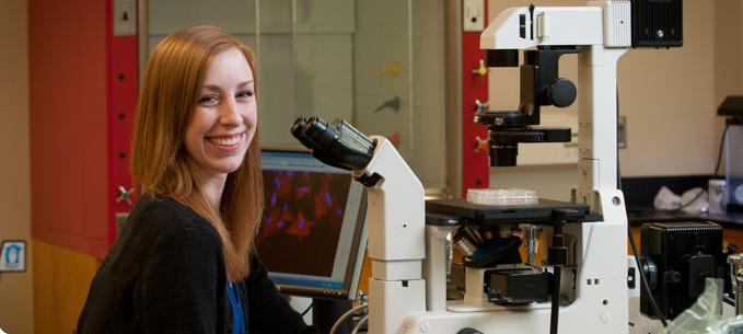 Kelly Widhammer sitting by high-tech microscope