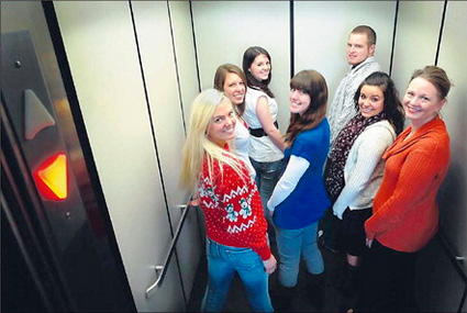 Seven students in an elevator, turn towards the camera