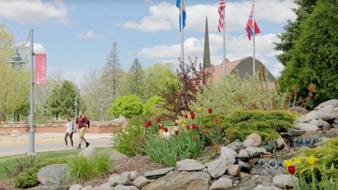 Students walking on campus past the flower garden