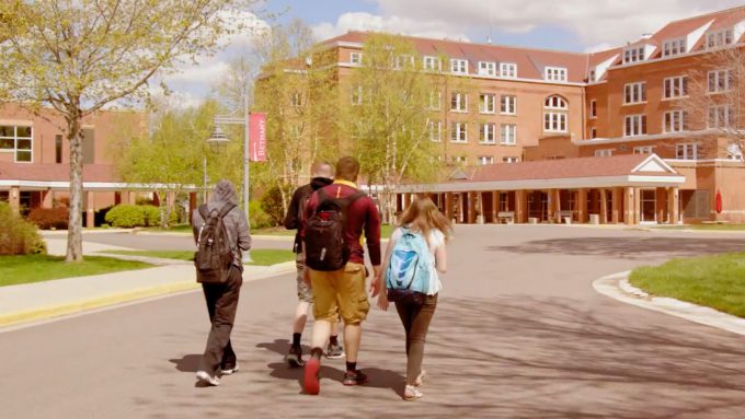 Four students walking on campus towards Old Main