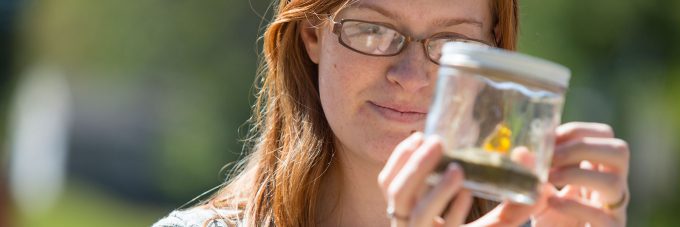 student looks at a substance in a container