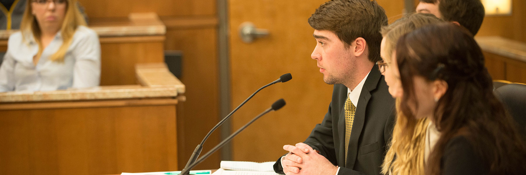 Male student speaking into microphone during a mock trial