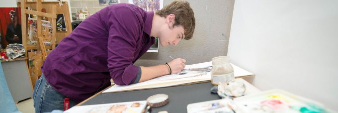 male student drawing on large canvas in art studio