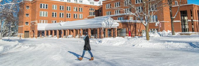 Female student walks by Old Main in winter