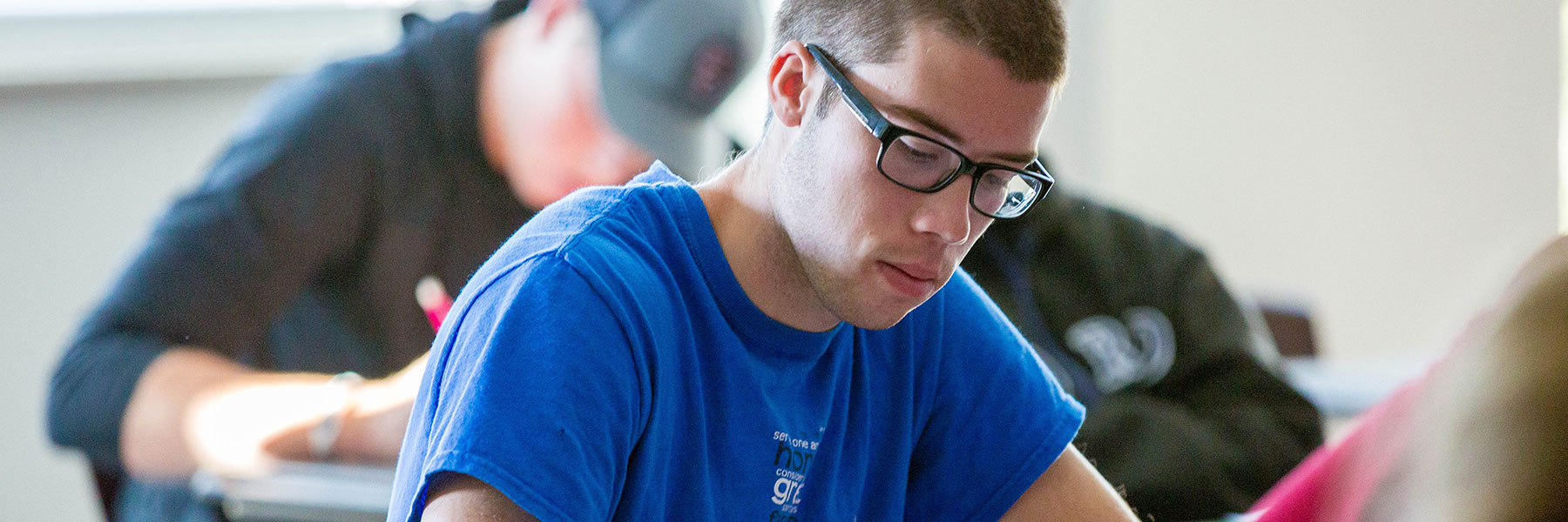 Male student taking notes during class