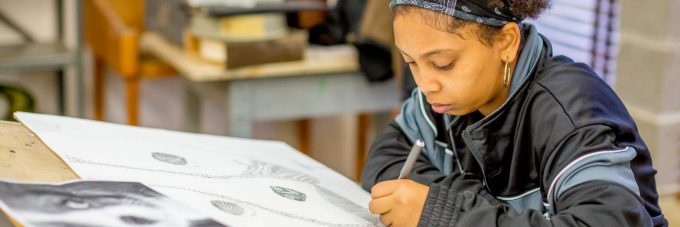 Female art student drawing with pen on paper in art studio