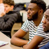 Two male students looking at speaker in class