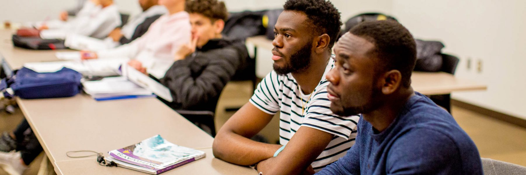 Two male students looking at speaker in class