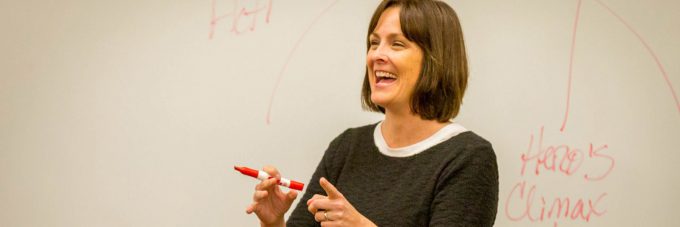 English professor smiles in front of whiteboard