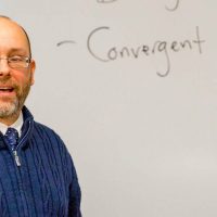 Psychology professor speaks in front of white board