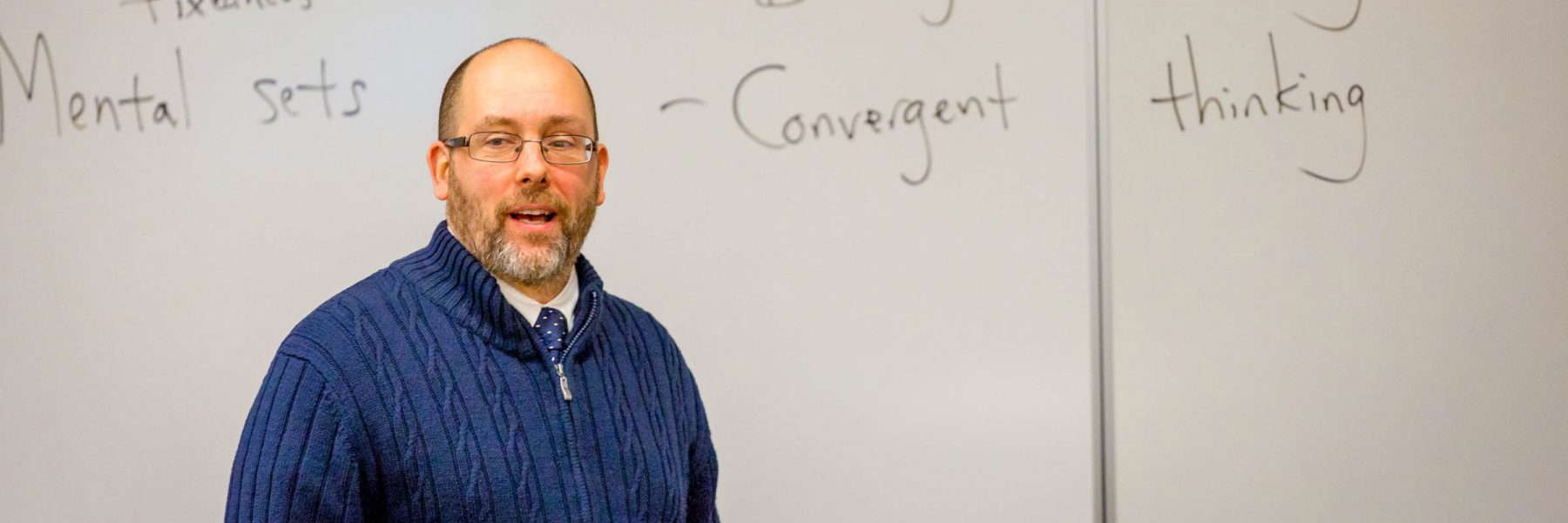 Psychology professor speaks in front of white board