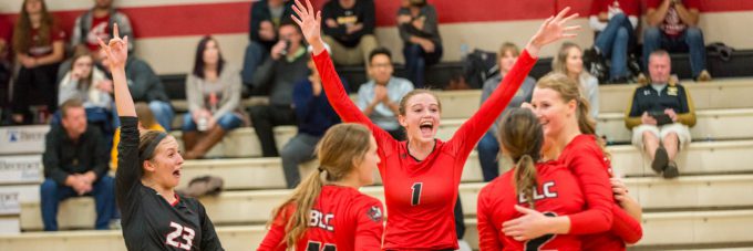 Women's volleyball players celebrate on the court