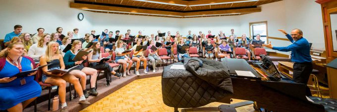 Prof. Dennis Marzolf directs a Bethany Concert Choir practice as they sing a hymn in Bethany's Silber Hall.