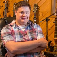 Professor Benji Inniger of the BLC Theater Department sits in his recording studio surrounded by musical instruments.