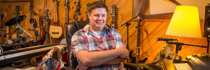 Professor Benji Inniger of the BLC Theater Department sits in his recording studio surrounded by musical instruments.