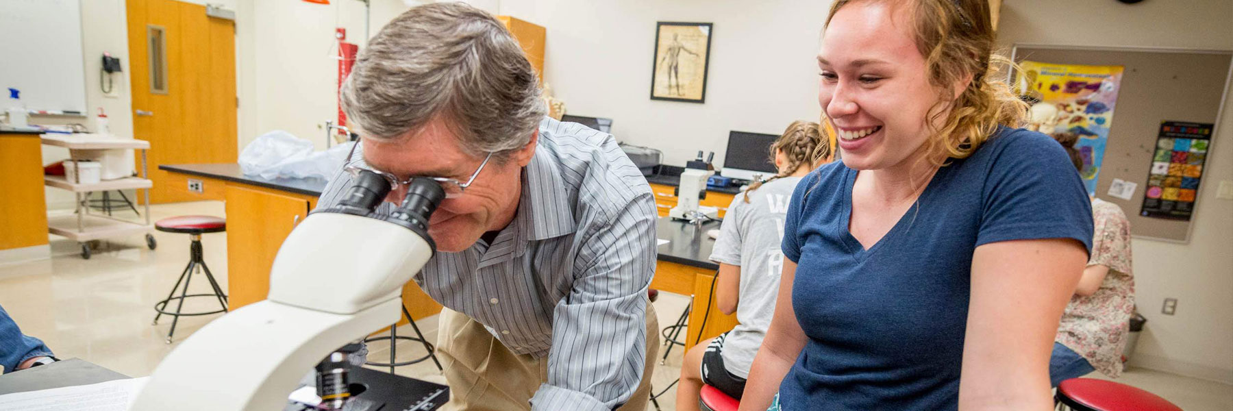 Prof. Doyle Holbird looks into a microscope in the Bethany biology lab.