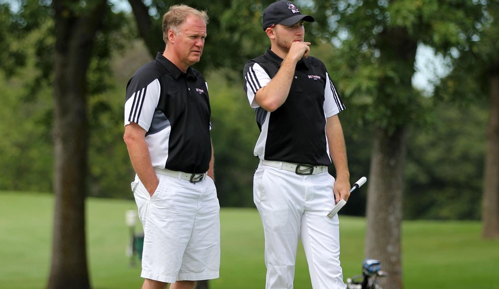 Daniel Mundahl (coach) and unnamed student golfer stand on the green