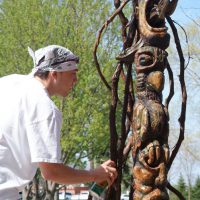 Wooden totem sculpture by Pipal, displayed on the campus green.