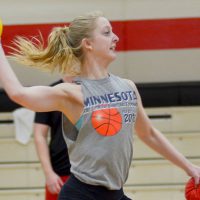 A student in the gymnasium throws balls during an intramural game as other students look on.