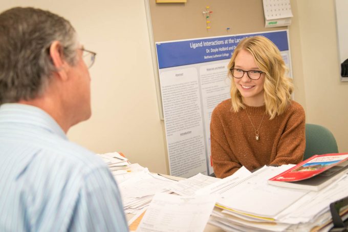 Student sitting and talking with professor across a desk