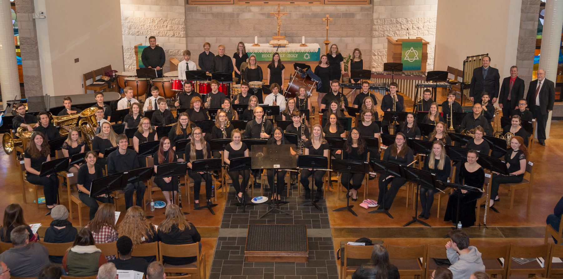 Group photo of performers with their instruments at the 2018-10 Concert Band Invitational, seated at the front of the chapel