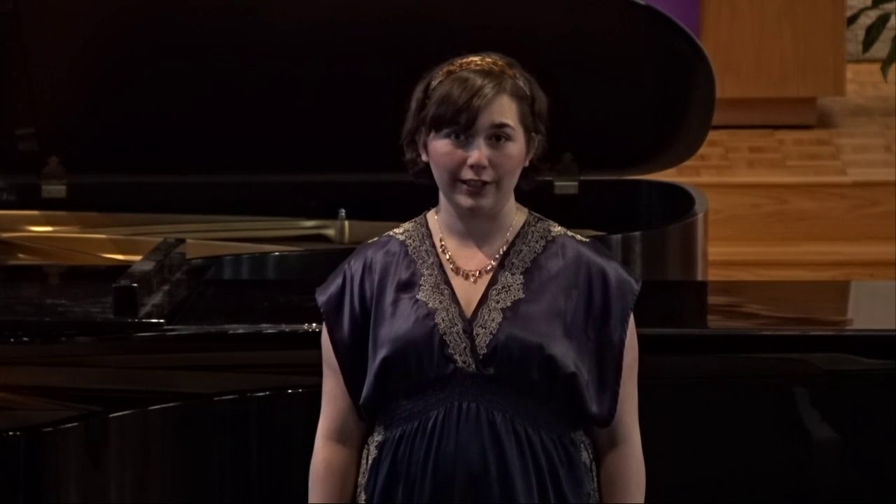 Student Bailey Schmidt sings in front of a grand piano in Trinity Chapel during her recital.