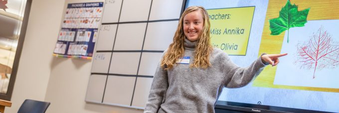 Elementary education student points at leaf on electronic display board