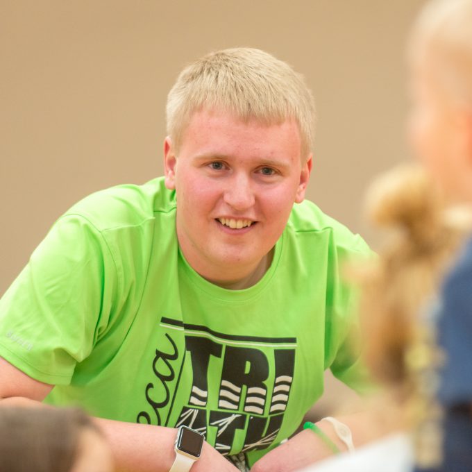 Education major Noah Battenfeld in gym with young students.