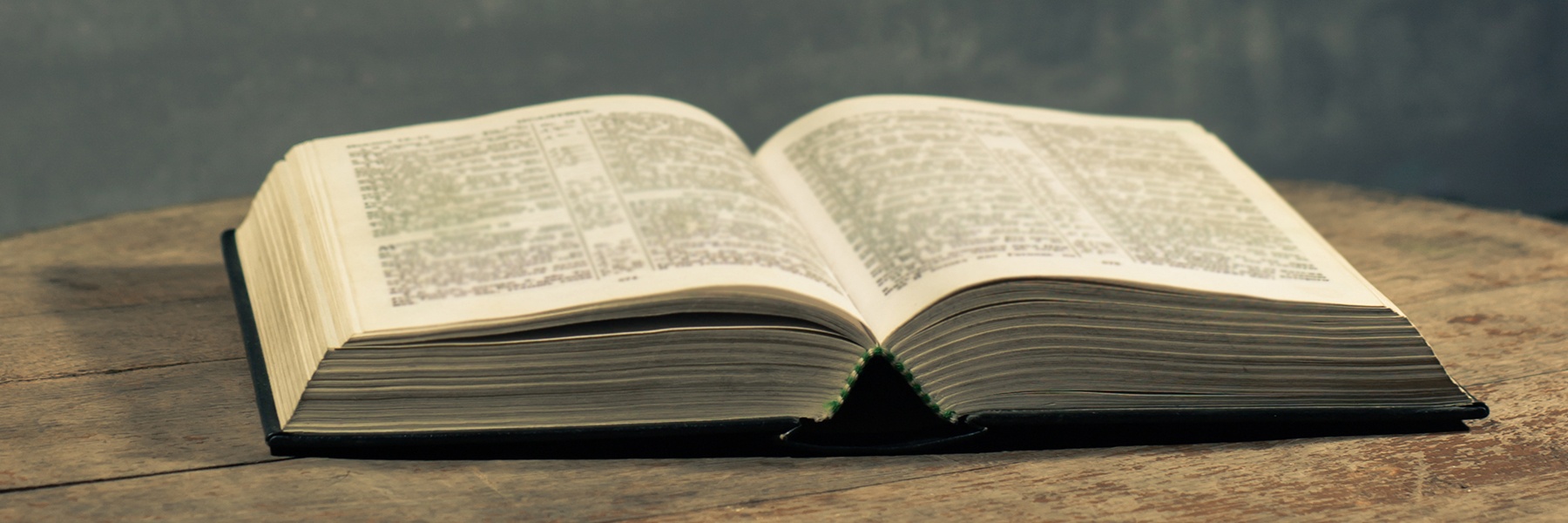 Bible open and sitting on wood table.