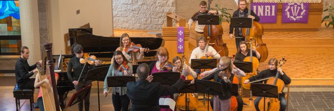 orchestra members play musical instruments in chapel