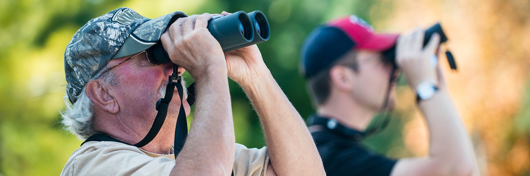 Two birdwatchers use binoculars to view and count hawks as part of Bethany's Hawkwatch