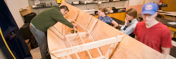 Students assemble a boat made of wood for a physics class lab