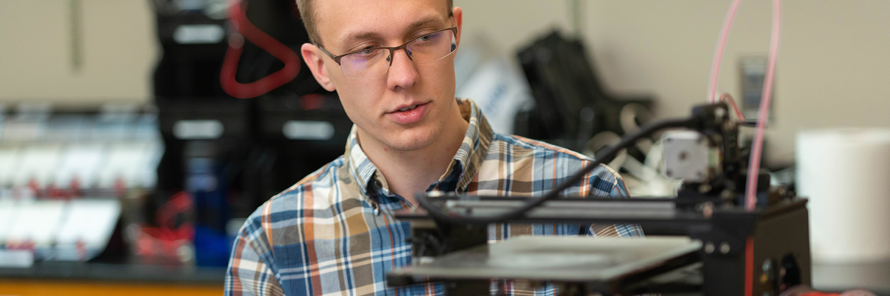 student working on 3d printer in physics lab