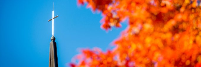 chapel steeple with sky background and fall leaves from a tree