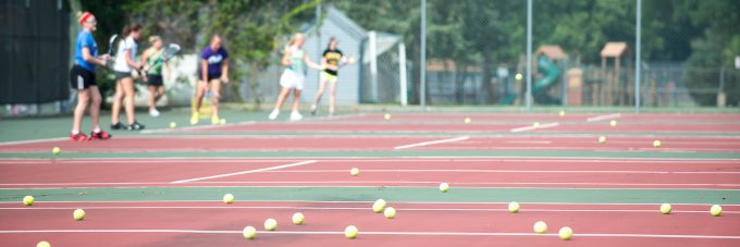 tennis courts with ball scattered on them