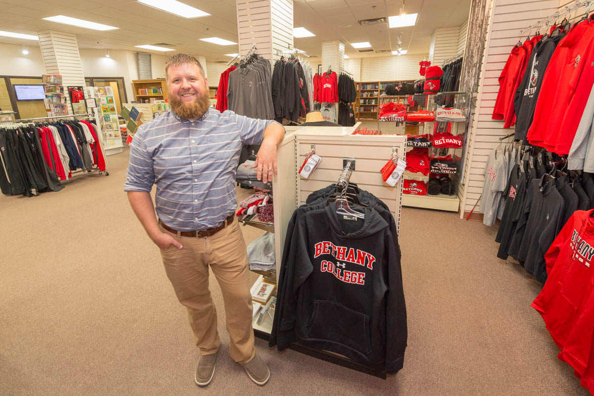 Bookstore manager Dan Gerdts poses by a rack of sweatshirts in the spirit store