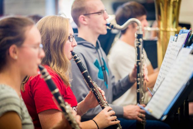 Members of the band play their reed instruments while reading the music