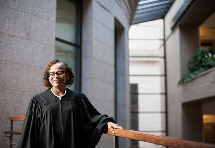 Image featuring Justice Natalie Hudson wearing black robe standing at a railing