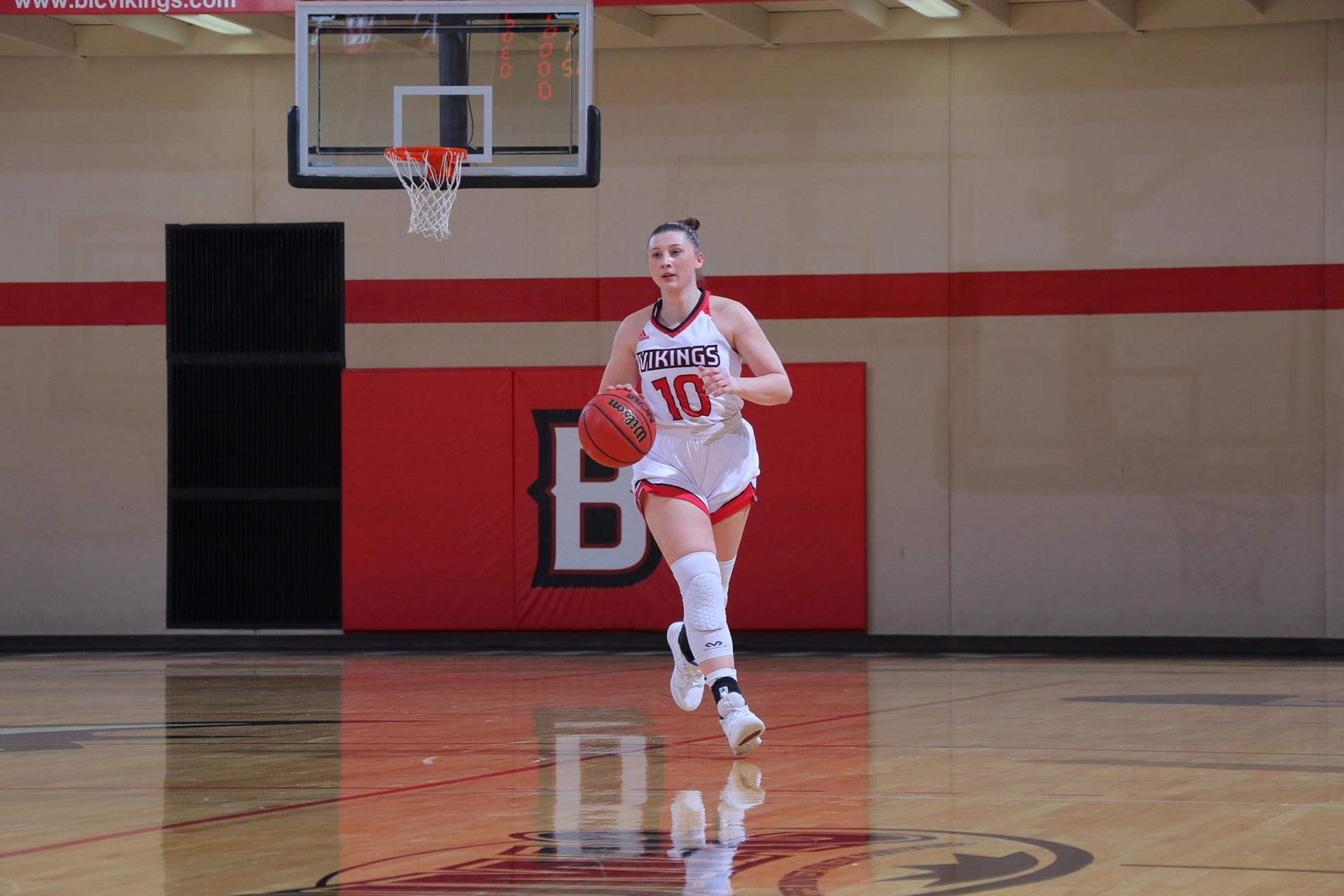 Women's basketball player (#10) dribbles the ball down the court