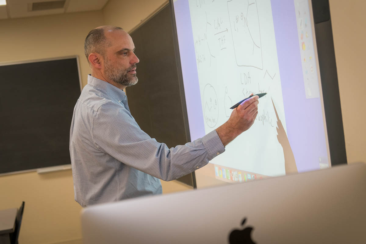 Dr. Eric Woller draws on an electronic smart board for a chemistry lesson