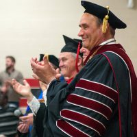 Bethany President Gene Pfeifer clapping at a commencement ceremony