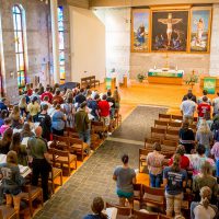 students, faculty, and staff standing in rows of chairs during a chapel service in trinity chapel