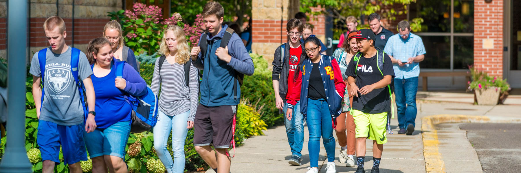 many students walk along a sidewalk beside trinity chapel