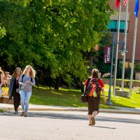 students walk across campus on sidewalks in between classes