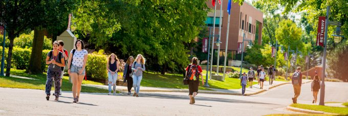 students walk across campus on sidewalks in between classes