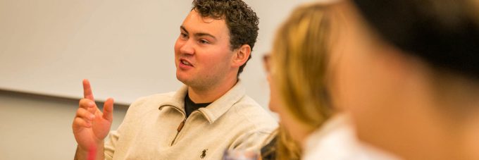 a male student talks and gestures with his hands during a classroom discussion